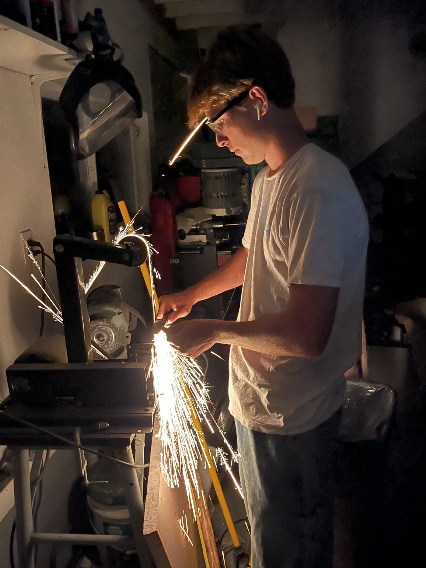 Sparks flying as a Schenk Engineering team member grinds a metal part in the shop