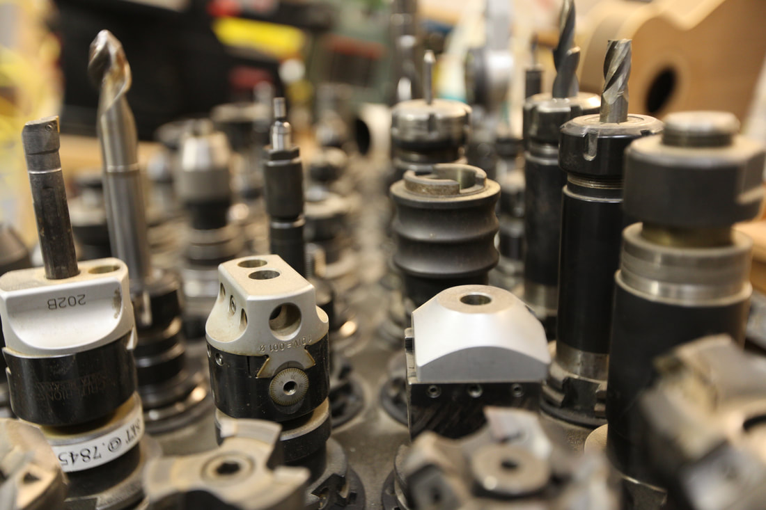 Wall of precision tool holders and end mills ready for the CNC at Schenk Engineering